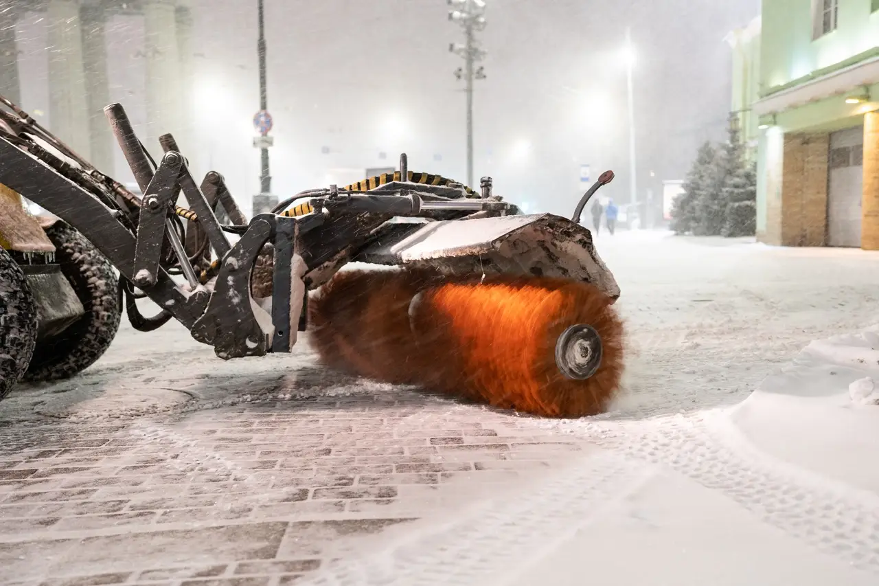 Traktor mit Kreiselbesen, der nach Schneefall professionell von Schnee und Eis befreit.