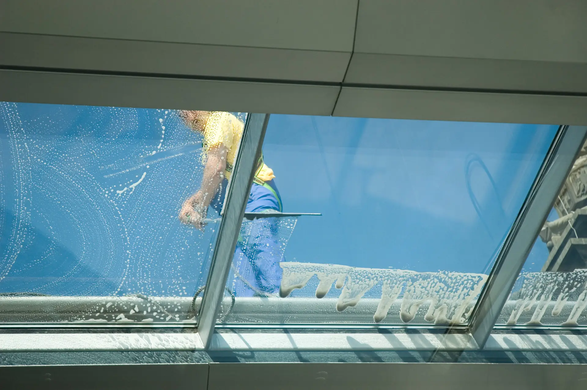 Professionelle Reinigungskraft reinigt großflächige Dachfenster.